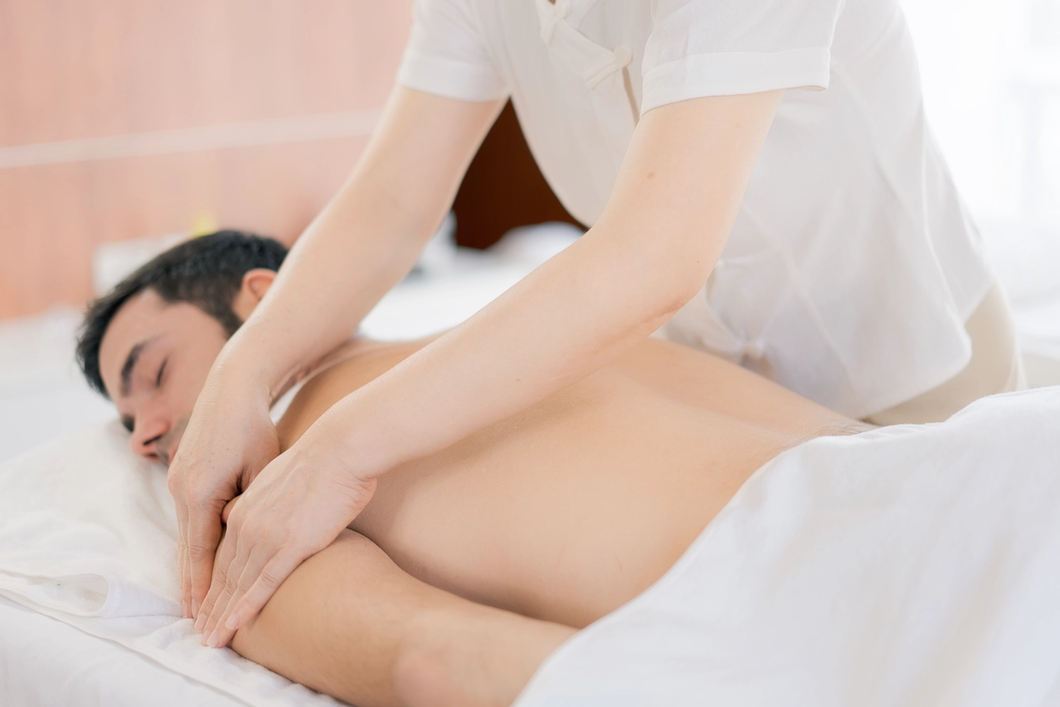 HeilOase - heile von innen - Ein Mann liegt auf dem Bauch und lässt sich in einem Spa professionell die Schultern massieren.